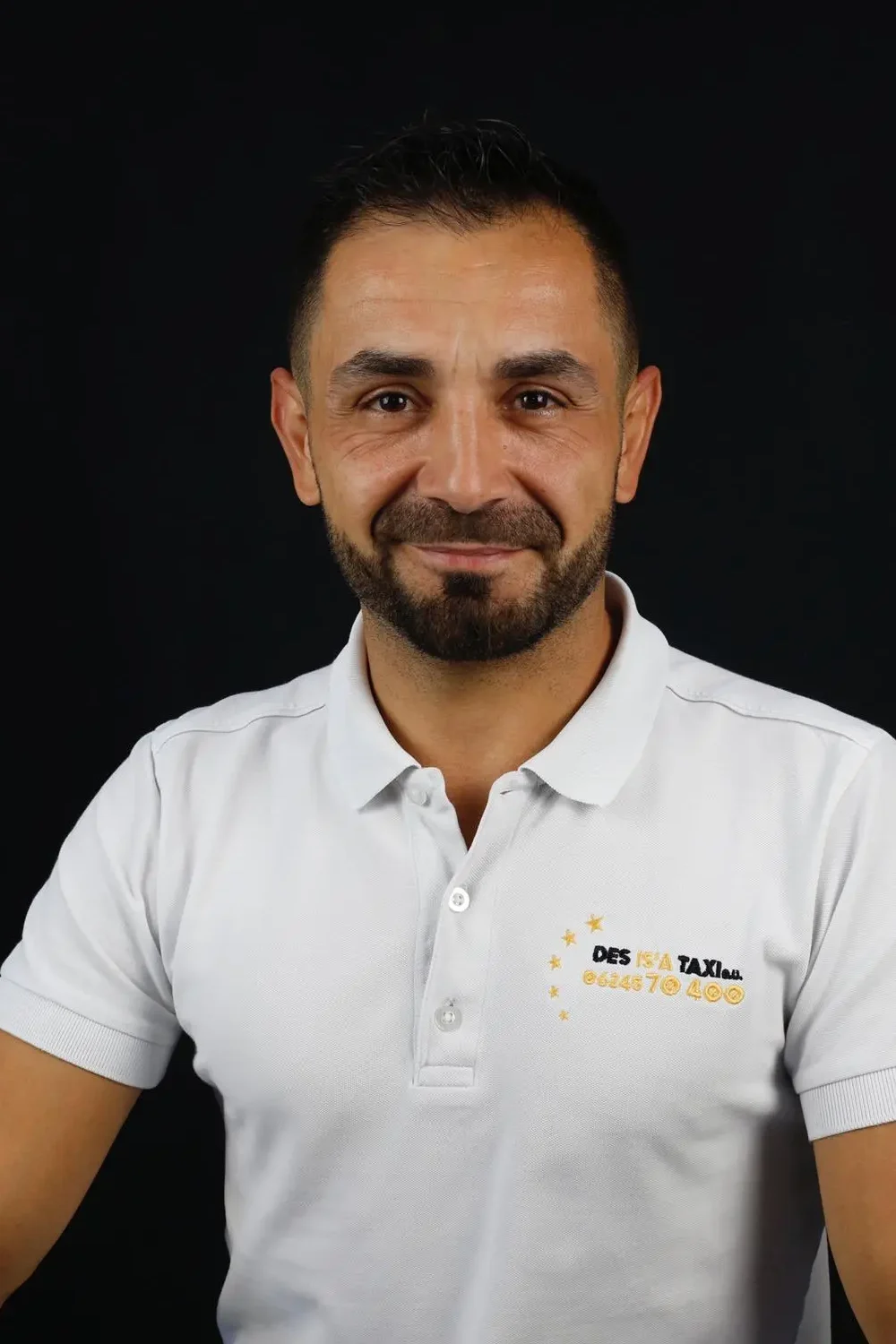 Porträt des Geschäftsführers von DES IS'A TAXI im weißen Firmenpolo mit Logo
