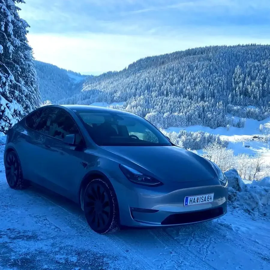 Tesla Taxi von Taxi Hallein auf verschneiter Bergstraße mit winterlicher Landschaft im Hintergrund